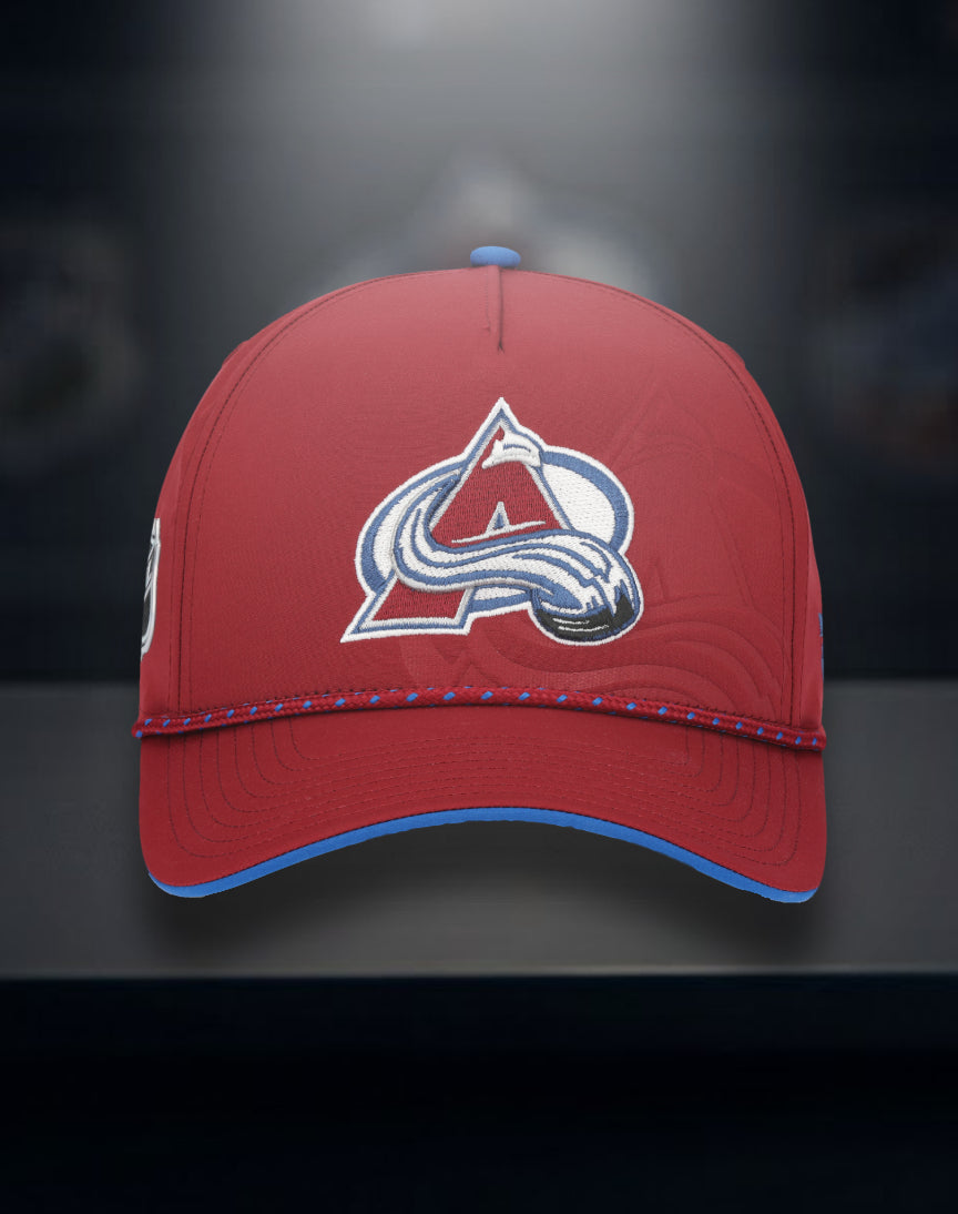  Front view of a  Burgundy Hat with Avalanche Logo in center with a larger Avalanche tonal logo behind main logo, blue Fanatics logo on front left  panel, burgundy rope with blue diamonds.  Bottom bill has blue, black background with a light beaming down