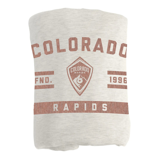 A folded light oatmeal colored blanket featuring a distressed brown Colorado Rapids graphic print, shown against a plain white background.