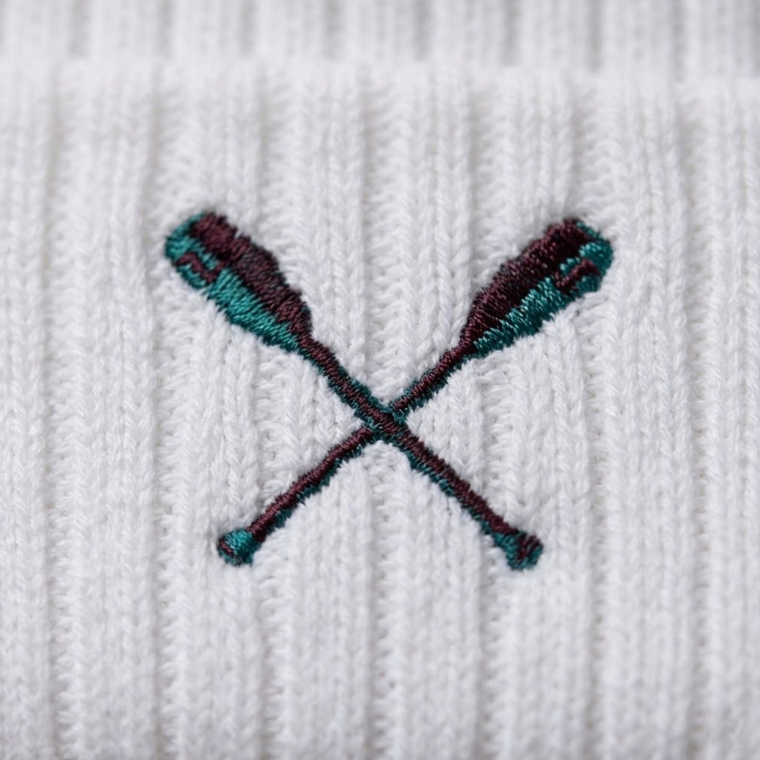 Embroidered design of crossed oars on a white fabric background
