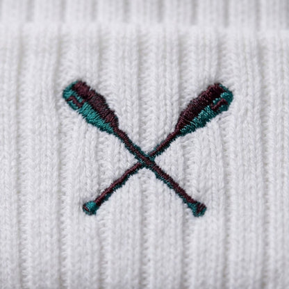 Embroidered design of crossed oars on a white fabric background